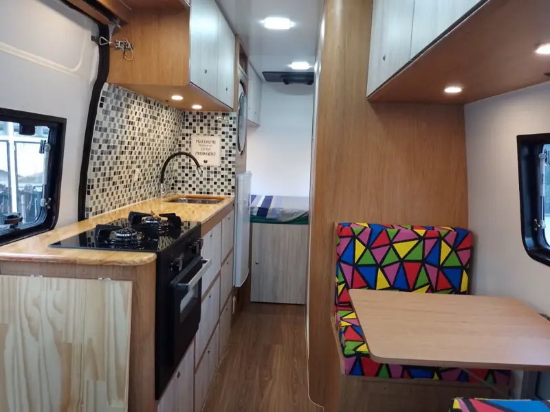 Interior de uma van montada pela Camper RJ, com cozinha, armários e mesa
